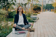 © VK Studio - Calm business woman meditating in lotus outdoors, peaceful female freelance employee practicing yoga