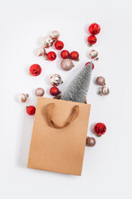 Christmas Tree In A Craft Gift Bag, Decorative Balls On A White Background. Top View, Flat Lay.