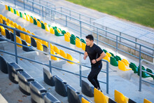 Asian Male Runner Running Around Modern Urban Stadium Up Stairs Cardio Morning Jog Climbing Staircase Man Jogging Outdoor. Sport Man Athlete Workout In Steps, In City. Active Fitness Healthy Lifestyle