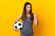 Young football player woman isolated on yellow background celebrating a victory in winner position