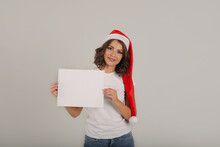 A Young Beautiful Girl In A White T-shirt Wearing A Santa Claus Hat Holds A White Sheet In Her Hands
