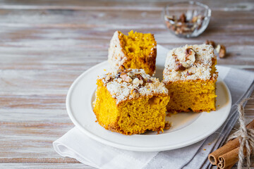 Wall Mural - Sliced pumpkin or carrot cake with streusel and walnuts on a white plate on a wooden background. Pumpkin baking recipes.