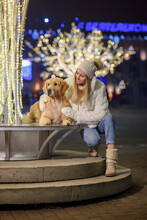 A Girl With A Golden Retriever Dog On A Winter Night In A City Decorated With Lights
