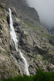 Fototapeta Do pokoju - Beautiful view of Midagrabin waterfall in sunlight in cloudy summer weather. Caucasus mountains. Russia. North Ossetia Alania