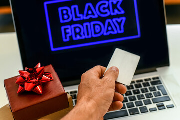 Hand with credit card in front of the laptop monitor doing purchases in an on line shop the black friday Purchase Christmas gifts E-commerce, tech, remote payment, new economy, shopping online concept