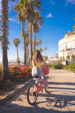Attractive Young Woman Riding Bike Near Beach With Palm Trees, Santa Monica, Los Angeles, California