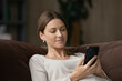 © fizkes - Calm attractive woman sit on sofa using smartphone, close up. Generation and modern tech everyday usage for fun, making distant order, communication remotely, web surfing, internet connection concept