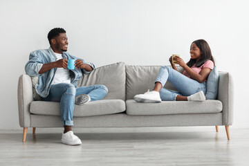 Canvas Print - African american couple drinking coffee sitting on couch