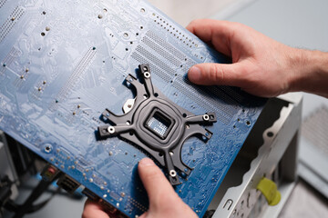 Wall Mural - A man holds a motherboard over a pc, close-up