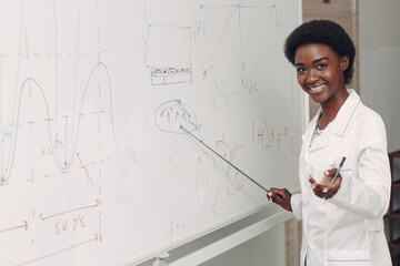 African American smiling black woman math teacher stands at white board with pointer.