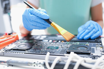 Poster - Man in gloves with a paintbrush cleans laptop parts