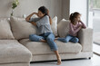 © fizkes - Unhappy mother and stubborn little daughter ignoring each other after quarrel, sitting on couch at home back to back, child and parent conflict concept, family misunderstanding and generation gap