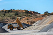 Large dump truck with the tipper raised unloading sand in a quarry.
