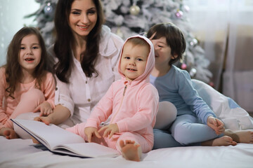 Wall Mural - A family with children having fun on the bed under the covers during the Christmas holidays.