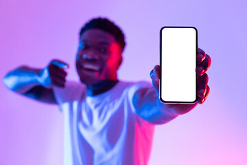 Poster - Millennial black man showing smartphone with empty white screen in neon light, selective focus. Mockup