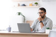 © Prostock-studio - Concentrated mature caucasian male businessman with beard in glasses look at laptop at kitchen interior