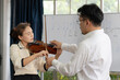 © plo - student learning how to play violin with teacher in classroom