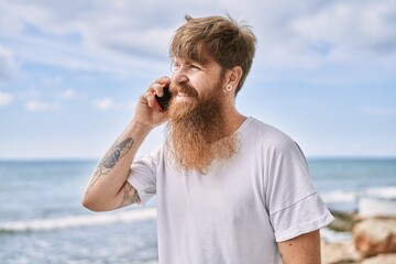 Sticker - Young redhead man smiling happy talking on the smarphone at the beach.