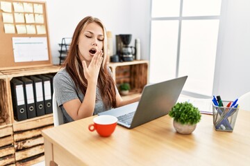 Poster - Young brunette woman working at the office with laptop bored yawning tired covering mouth with hand. restless and sleepiness.