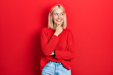 Sticker - Beautiful blonde woman wearing casual red sweater with hand on chin thinking about question, pensive expression. smiling with thoughtful face. doubt concept.