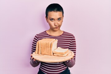 Sticker - Beautiful hispanic woman with short hair holding sandwich bread skeptic and nervous, frowning upset because of problem. negative person.