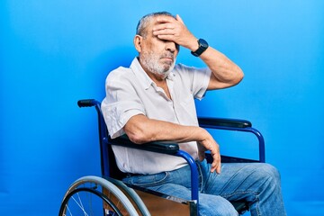 Canvas Print - Handsome senior man with beard sitting on wheelchair covering eyes with hand, looking serious and sad. sightless, hiding and rejection concept