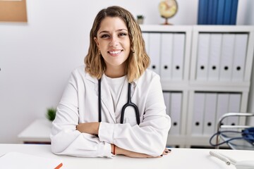 Young hispanic woman wearing doctor stethoscope with arms crossed gesture at clinic