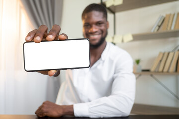 Digital marketing. Mobile app. Communication technology. Cheerful business man showing white empty mockup horizontal smartphone screen with copy space on defocused background.
