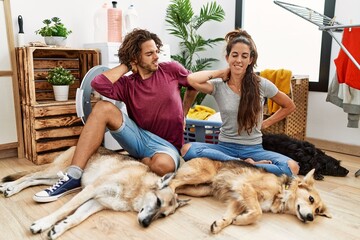 Sticker - Young hispanic couple doing laundry with dogs suffering of neck ache injury, touching neck with hand, muscular pain