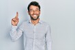 © Krakenimages.com - Handsome man with beard wearing casual elegant shirt pointing finger up with successful idea. exited and happy. number one.