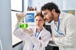 Man and woman scientist partners looking test tube at laboratory