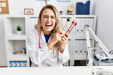 Sticker - Young beautiful doctor woman holding diapason instrument smiling and laughing hard out loud because funny crazy joke.