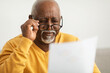 © Prostock-studio - Senior African Man Squinting Eyes Reading Papers Wearing Eyeglasses Indoor