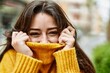 Young beautiful brunette woman wearing turtleneck sweater doing funny gesture covering face with sweater