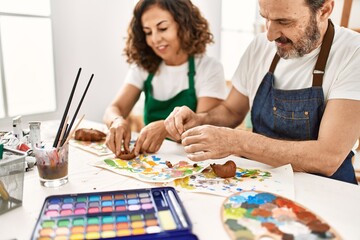 Canvas Print - Two middle age students smiling happy modeling clay sitting on the table at art school.