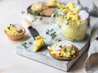 Tartlets with egg pate or salad and radish and thyme on light stone background. Egg dip in glass jar.