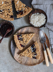 Wall Mural - Pieces of homemade shortcrust jam pie with crumble on concrete background. Traditional autumn or winter bakery. Top view.