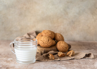 Wall Mural - Oatmeal cookies on wooden cutting board with a cup of milk, brown concrete background. Healthy snack or dessert.