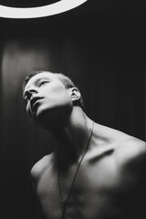  Young man posing to the camera with a naked torso for advertising. Black and white photography. Emotions, feelings. There is room for text. 