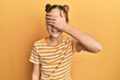 Beautiful brunette little girl wearing casual striped t shirt smiling and laughing with hand on face covering eyes for surprise. blind concept.