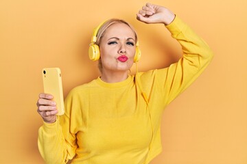 Canvas Print - Young blonde woman dancing wearing headphones looking at the camera blowing a kiss being lovely and sexy. love expression.