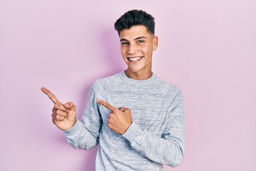 Sticker - Young hispanic man wearing casual clothes smiling and looking at the camera pointing with two hands and fingers to the side.