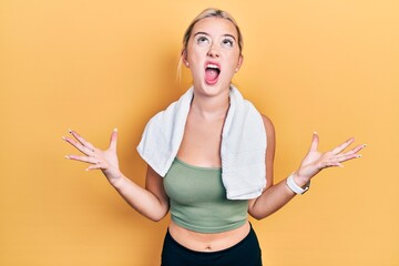 Wall Mural - Young blonde girl wearing sportswear and towel crazy and mad shouting and yelling with aggressive expression and arms raised. frustration concept.