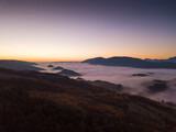 Fototapeta Niebo - Italy November 2021: aerial view of mountains with fog below in autumn season at sunset