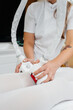 © Andrii - A young woman in a white suit, undergoing cosmetic LPG massage and laser lipolysis, close-up. Cosmetic procedure, in a medical center. Anti-cellulite procedures.