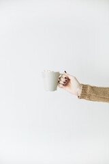 Women's hand hold mug with whipped cream on white background