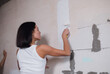 © kalinichenkod - young beautiful woman makes repairs in the apartment. the girl makes repairs at home on her own paints the walls