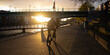Man riding a bike at the Weser promenade in Bremen, Germany at sunset with long shadows and the sun beaming below a bridge