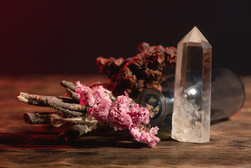 Empty glass bottle and dry herb on the old wooden table background. Witchcraft concept.