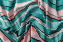 Draped Striped Fabric Of Teal And Orange Colors Background. Texture Of Folded Thin Cotton Cloth With Light And Dark Horizontal Lines. Crumpled Textile Surface As Design Element. Full Frame.